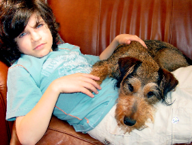 boy laying down with puppy on his lap