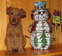 puppy sitting on a mantle next to a snowman decoration